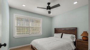 A bedroom with a bed, a nightstand, a lamp, a ceiling fan, and a window with blinds. - Adorable 3-bedroom house with in minutes I-40 and half a mile from 540 (Fort Smith)