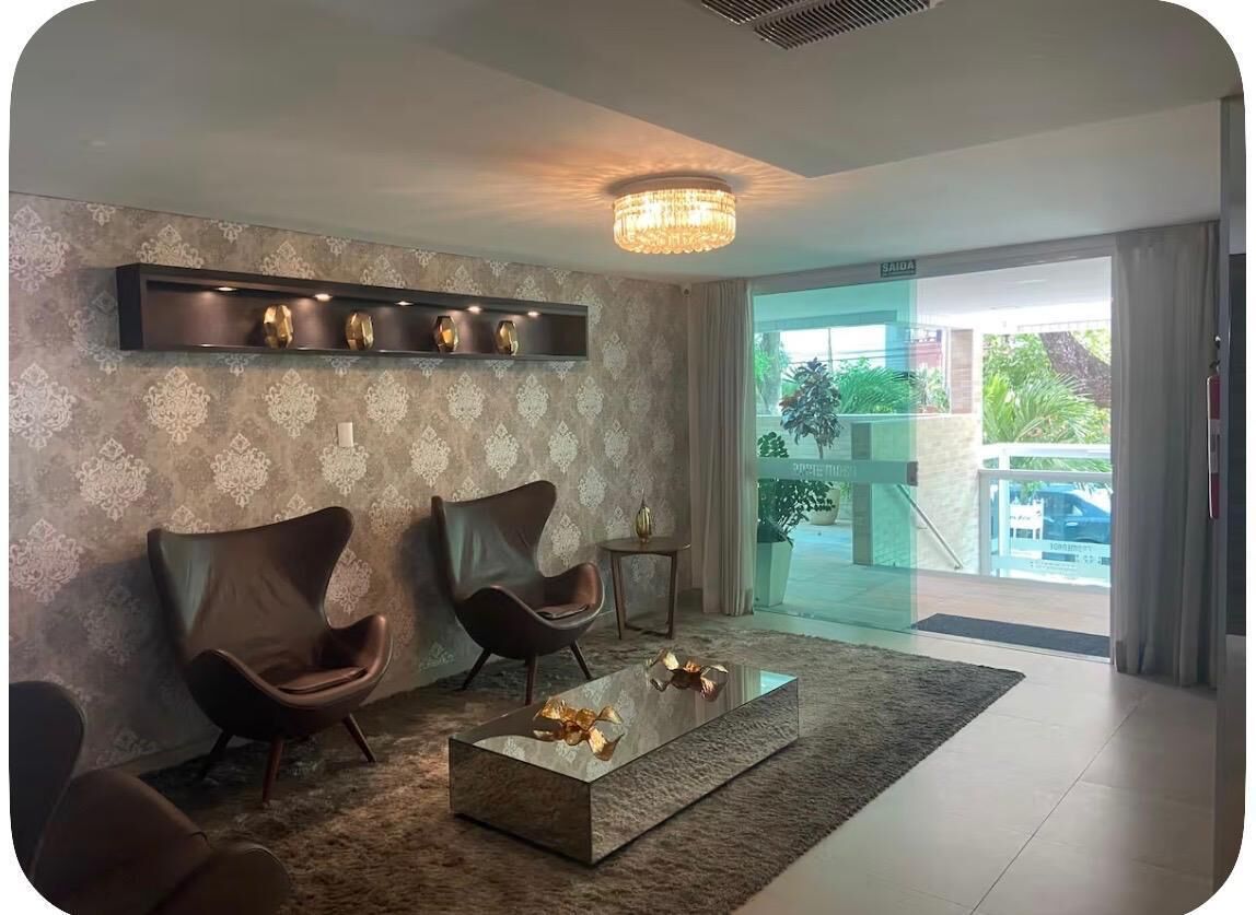 A modern living room with a chandelier, two leather armchairs, a glass coffee table, and a patterned wallpaper.