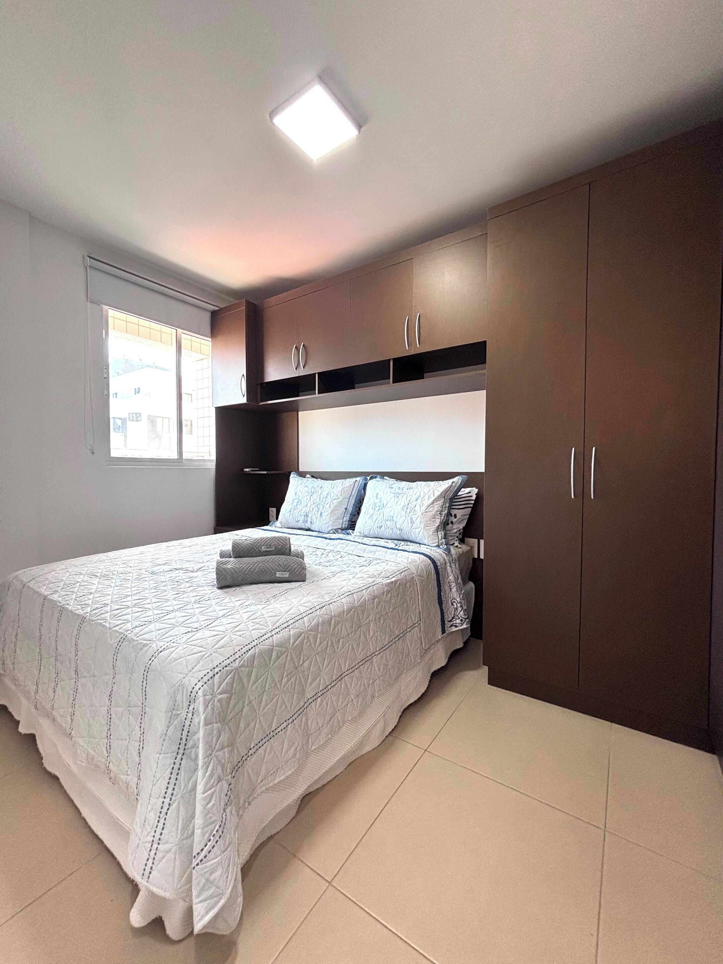 A bedroom with a bed, a window, and built-in wardrobes.