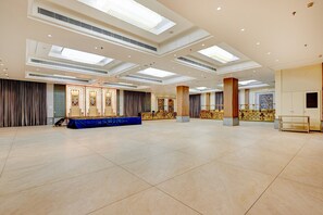 A spacious hall with a high ceiling, recessed lighting, and a blue stage area. - Classic Palette Hotel and Resort (Cuttack)