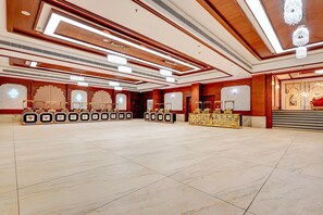 A spacious hall with a high ceiling, chandeliers, and a marble floor.