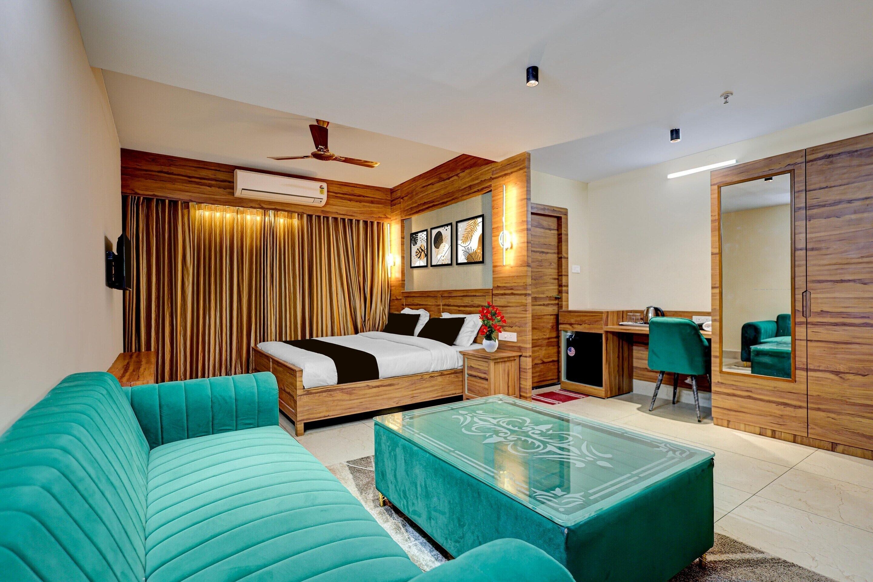 A modern hotel room with a bed, a sofa, a desk, and a mirror.