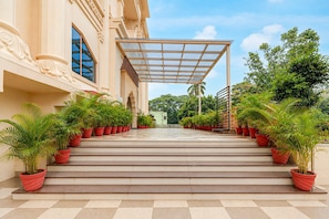 A grand entrance with a covered walkway leading to a building, flanked by rows of potted plants. - Classic Palette Hotel and Resort (Cuttack)