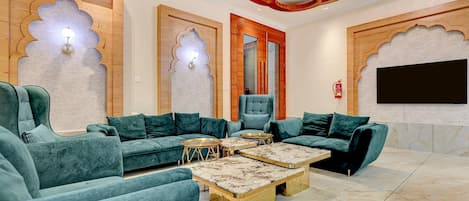 Una sala de estar moderna con un sofá seccional, sillones, una mesa de centro y un televisor de pantalla plana montado en la pared.