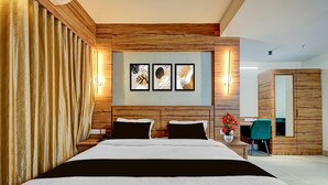 Une chambre moderne avec une tête de lit en bois, un lit avec une literie blanche et noire, une table de chevet avec un téléphone et un luminaire fixé au mur.