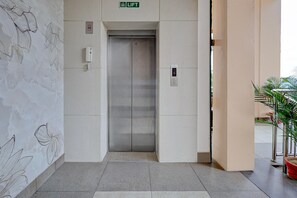 An elevator with a digital display, a lift sign, and a wall with abstract line drawings.