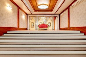 A grand staircase leading to a room with a red upholstered chair and ornate decor. - Classic Palette Hotel and Resort (Cuttack)