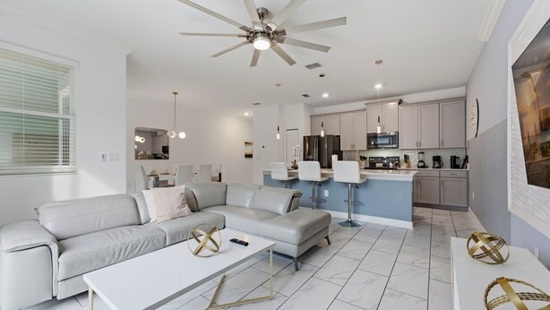 A modern living room with a sofa, coffee table, and a ceiling fan. - Family Friendly Home, Private Pool, Near Disney (Kissimmee)
