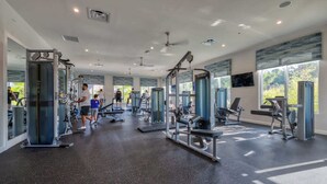 A spacious gym with various exercise machines, large windows, and a ceiling fan. - Family Friendly Home, Private Pool, Near Disney (Kissimmee)