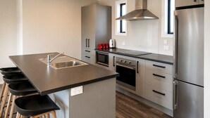 Et moderne køkken med en central ø, rustfrie stålapparater og barstole.