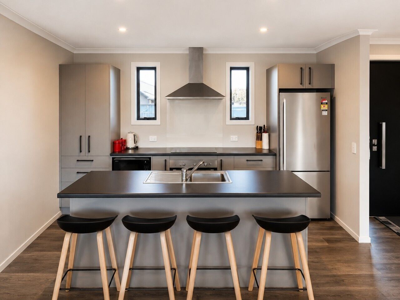 Una cocina moderna con una isla central, electrodomésticos de acero inoxidable y taburetes de bar.