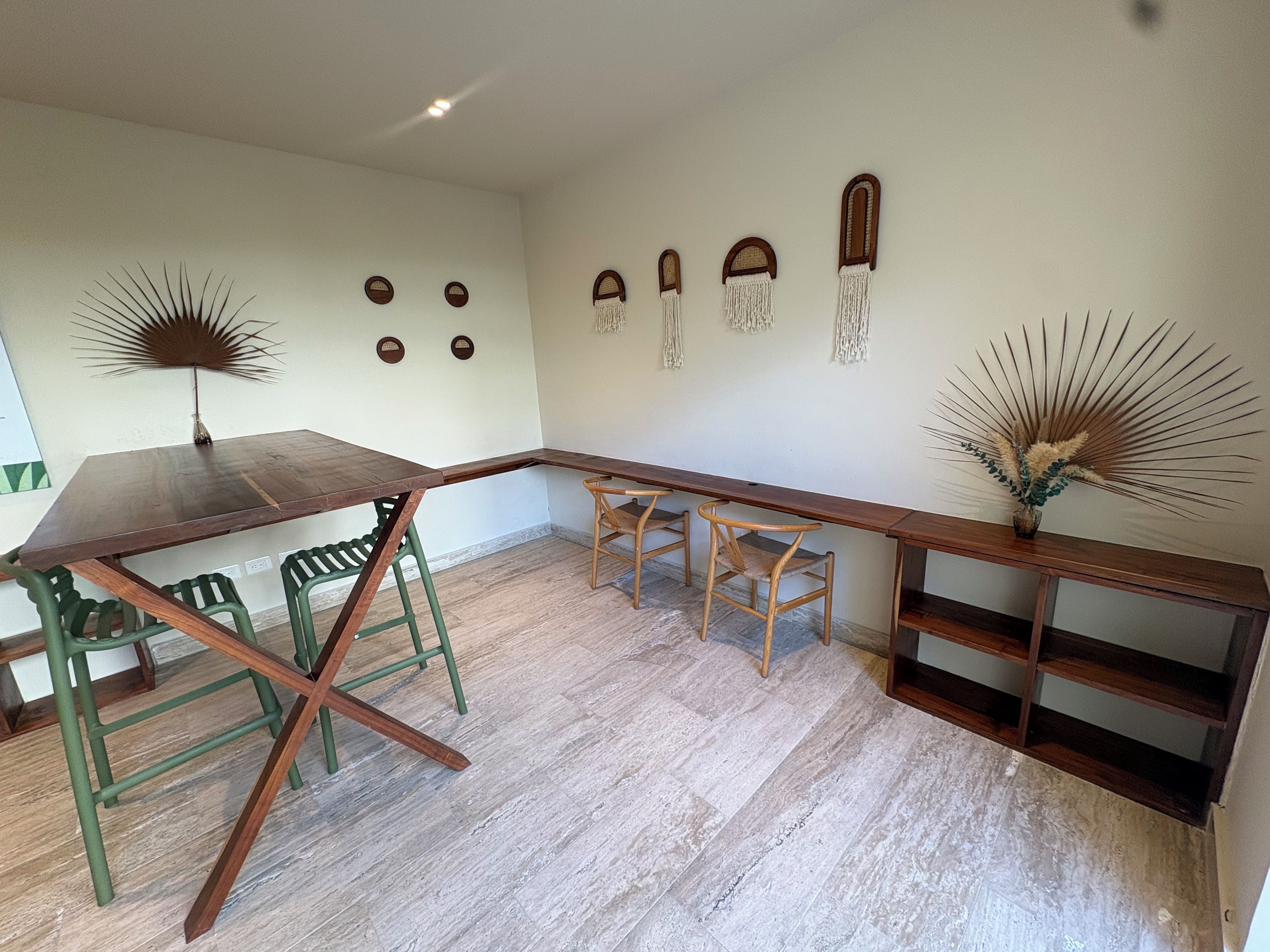 Een eetruimte met een houten tafel en stoelen, een decoratief wandobject en een klein plankje met een plant.