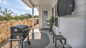 An outdoor patio with a grill, a small table, and a potted plant. - Modern 4-bedroom Family Home Near Downtown Austin (Manchaca)