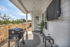 Eine Terrasse im Freien mit Grill, kleinem Tisch und einem Blumentopf.