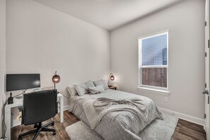 Ein Schlafzimmer mit einem Bett, einem Schreibtisch mit Stuhl, einem Fernseher und zwei Wandleuchten.