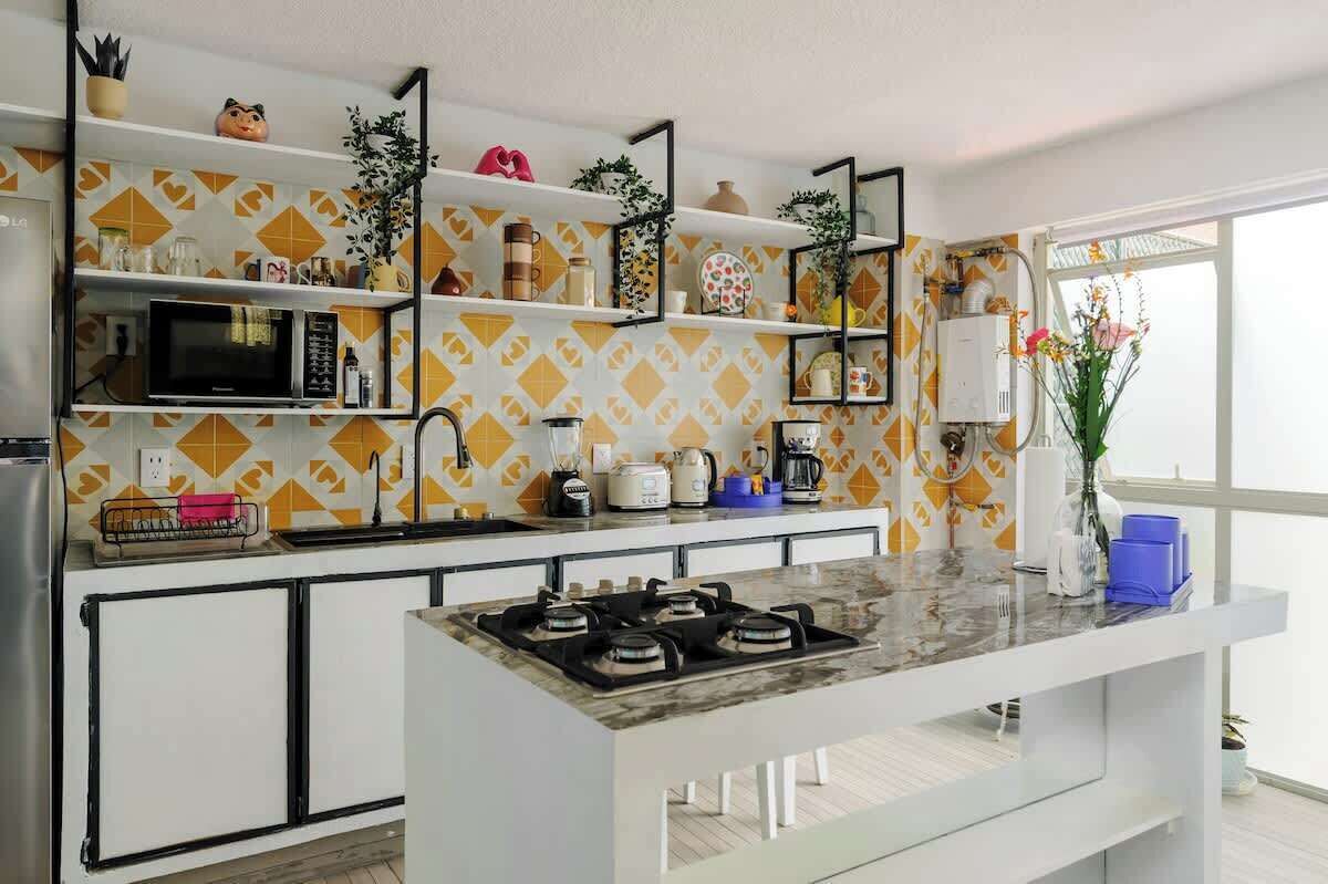 A modern kitchen with a central island, built-in appliances, and decorative shelves.