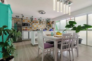 Eine moderne Küche mit Essbereich, weißen Schränken und einem großen Fenster.
