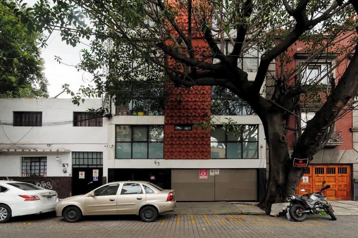 A building with a garage door, a tree in front, and parked cars.