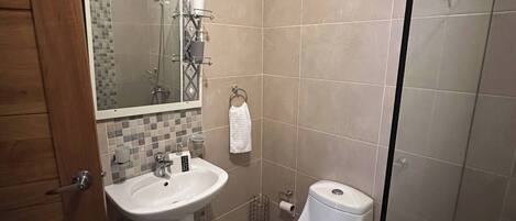 A bathroom with a shower, toilet, and sink.