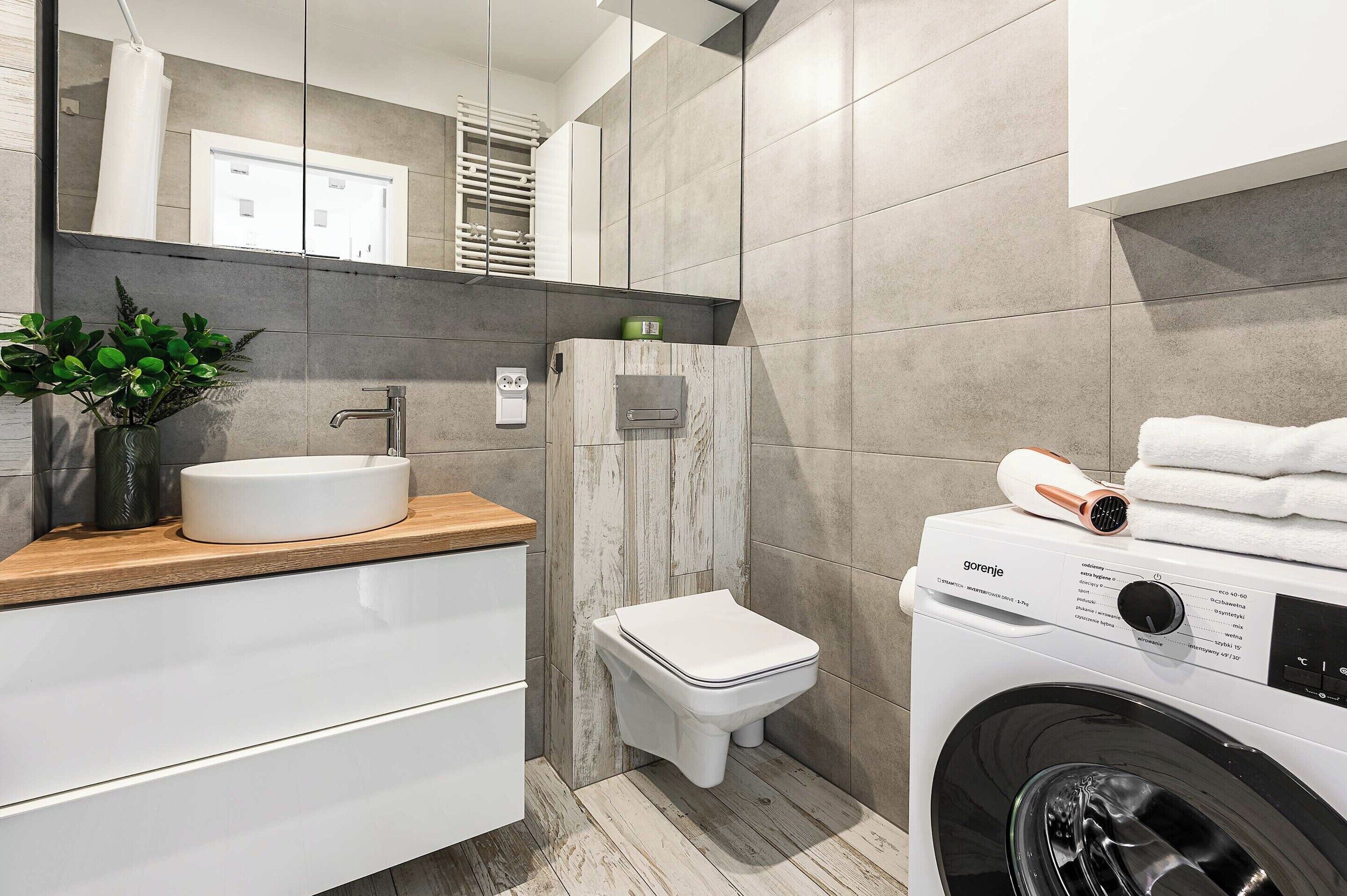 A modern bathroom with a sink, toilet, and washing machine.