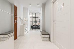 A hallway with a wooden door on the left, a white cabinet with drawers, and a bench on the right. - Family Flat With Garden (Warsaw)