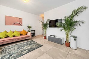 A modern living room with a sofa, a flat-screen TV, and potted plants. - Home Near Warsaw Spire (Warsaw)