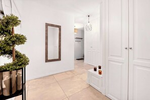A hallway with a mirror, a potted plant, and a door leading to a kitchen area. - Home Near Warsaw Spire (Warsaw)