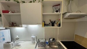 Una cocina con mostrador blanco, un lavamanos y un armario arriba.