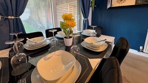 A dining table set with plates, glasses, and a vase of flowers. - Modern 3BR Home with Free Parking | Sleeps 6 | Family & Business Friendly (Bracknell)