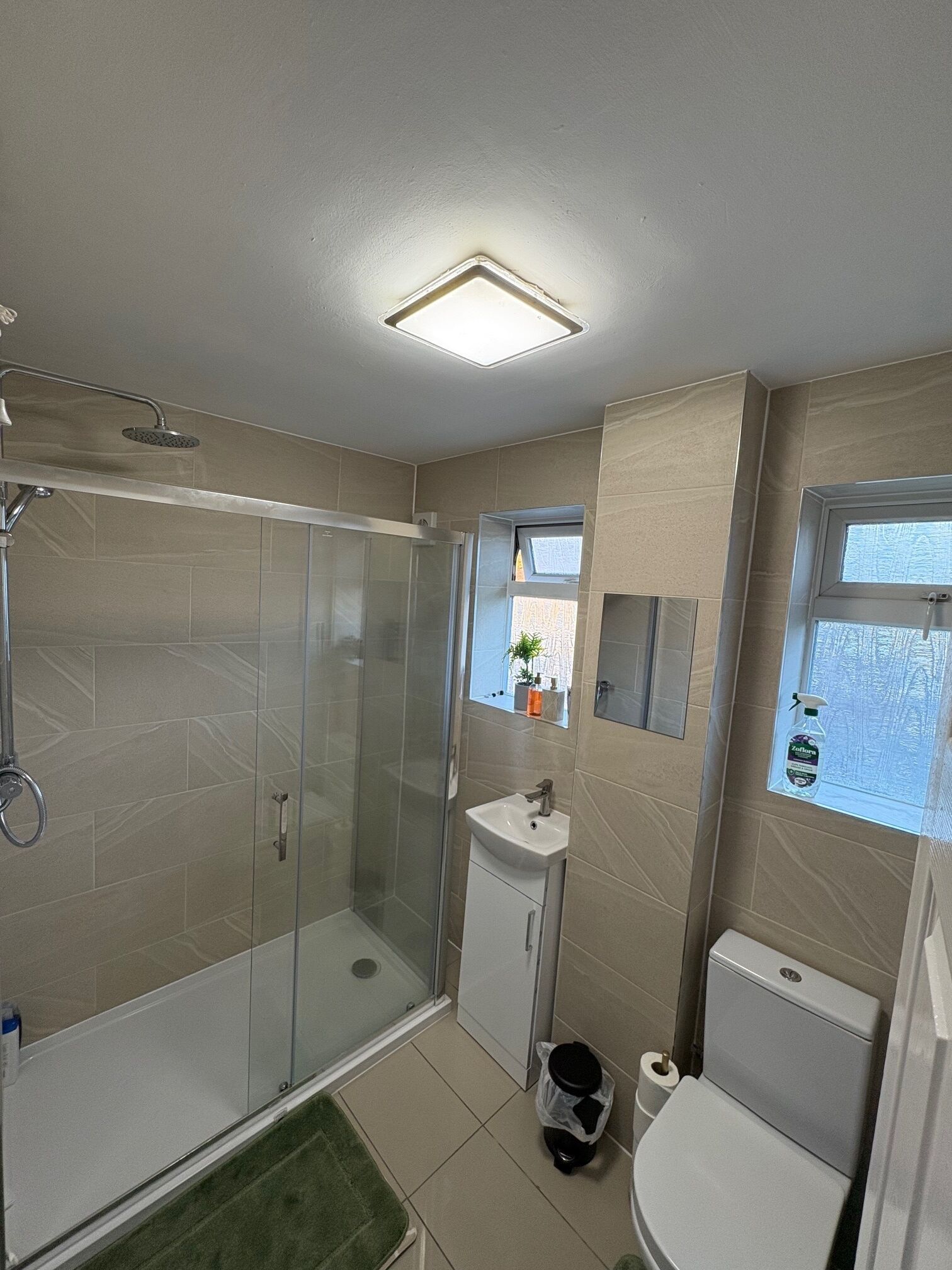 A bathroom with a glass-enclosed shower, a sink, and a toilet.