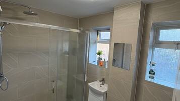 A bathroom with a glass-enclosed shower, a sink, and a toilet.