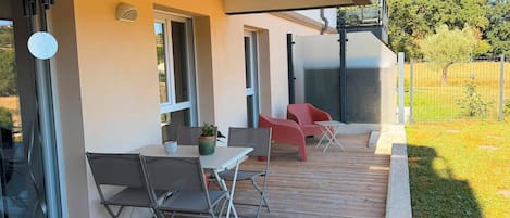 A modern outdoor seating area with a table, chairs, and a potted plant.