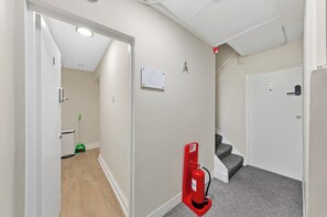 A hallway with a fire extinguisher, a door, and a staircase. - Luxury one bedroom apartment sleeps up to 4 people (London)
