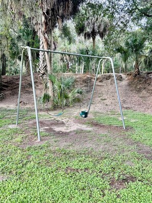 A swing set in a grassy area with trees in the background. - 2-bedroom RV in Crystal River (Crystal River)