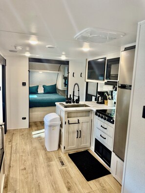 A compact kitchen with a sink, stove, and microwave. - 2-bedroom RV in Crystal River (Crystal River)