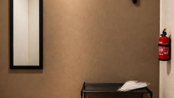 Ein Zimmer mit Holzboden, einer Bank, einem Spiegel und einem Feuerlöscher an der Wand.