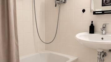 A modern bathroom with a bathtub, a shower, and a sink.