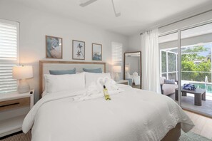 Een hotelkamer met een groot bed, twee nachtkastjes met lampen, een grote spiegel en uitzicht op het omliggende landschap.