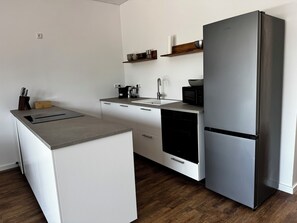 Una cocina moderna con un refrigerador de acero inoxidable, lavavajillas integrado y un microondas.
