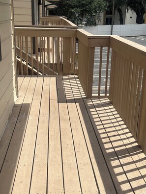 A wooden deck with a metal railing, leading to a building entrance. - The Doak Lookout - 2BR Condo Overlooking Stadium and Minutes from Campus (Tallahassee)