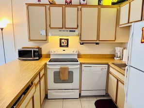 A compact kitchen with a microwave, stove, dishwasher, and refrigerator. - The Doak Lookout - 2BR Condo Overlooking Stadium and Minutes from Campus (Tallahassee)