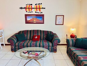 Ein Wohnzimmer mit einer Couch, einem Couchtisch und zwei gerahmten Bildern an der Wand.