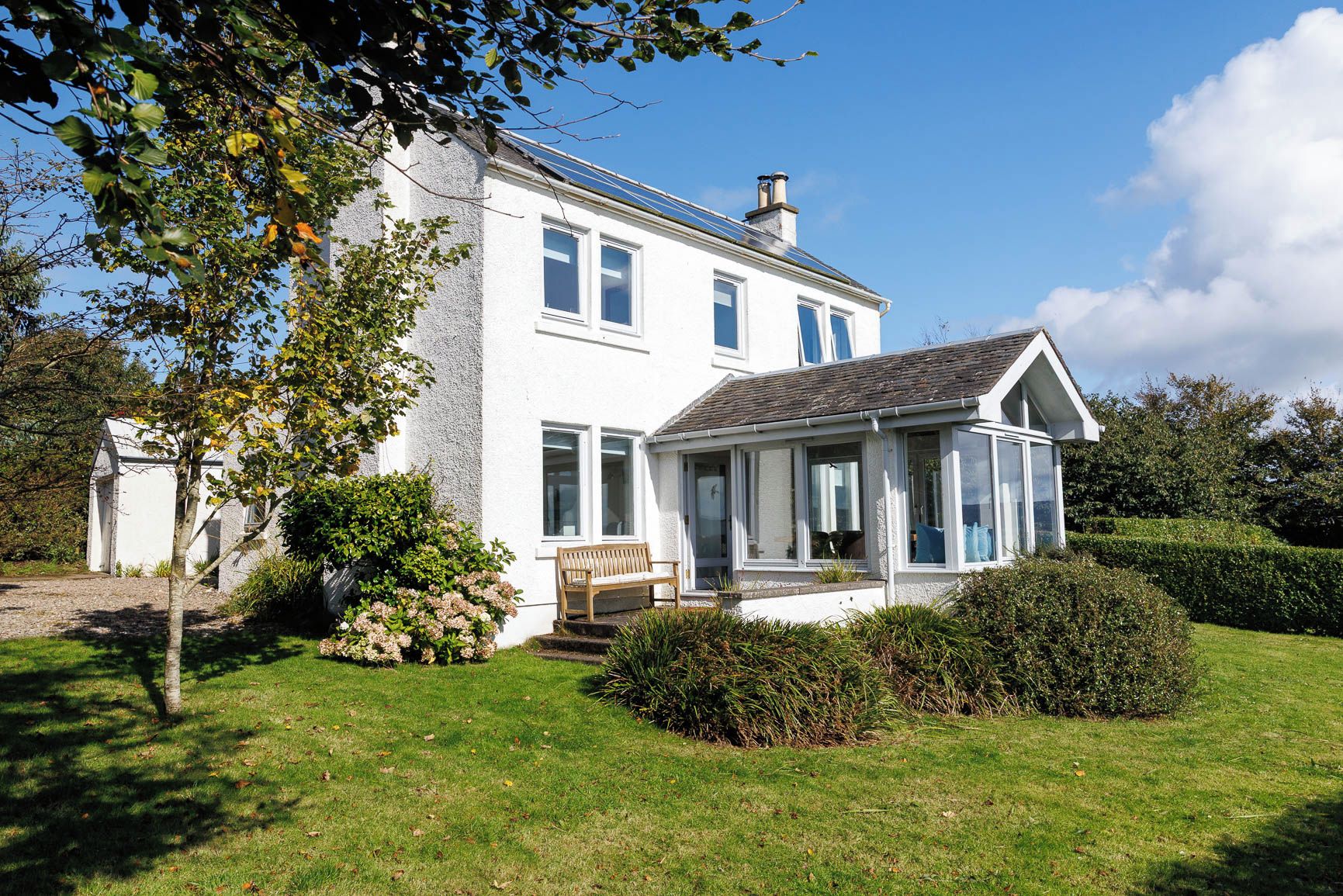 A white two-story house with a covered porch and a small garden.