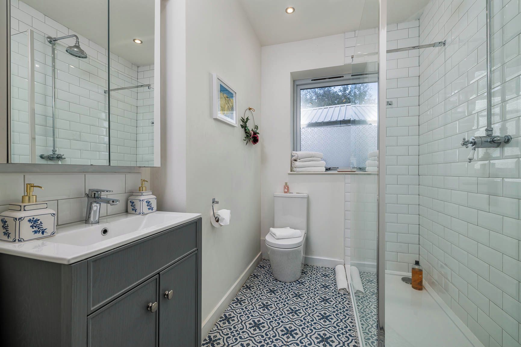 Un baño con cabina de ducha de vidrio, inodoro blanco y lavamanos con espejo.
