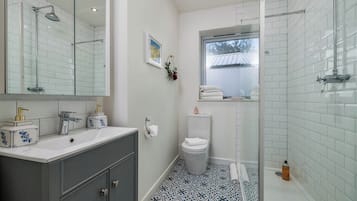 A bathroom with a glass shower enclosure, a white toilet, and a sink with a mirror.