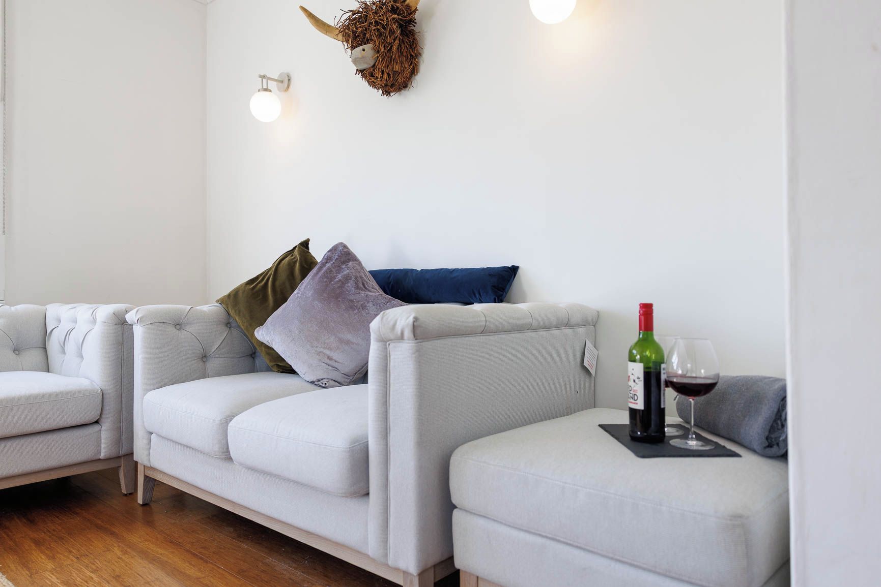 A modern living room with a sofa set, decorative wall art, and a wine bottle on a small table.