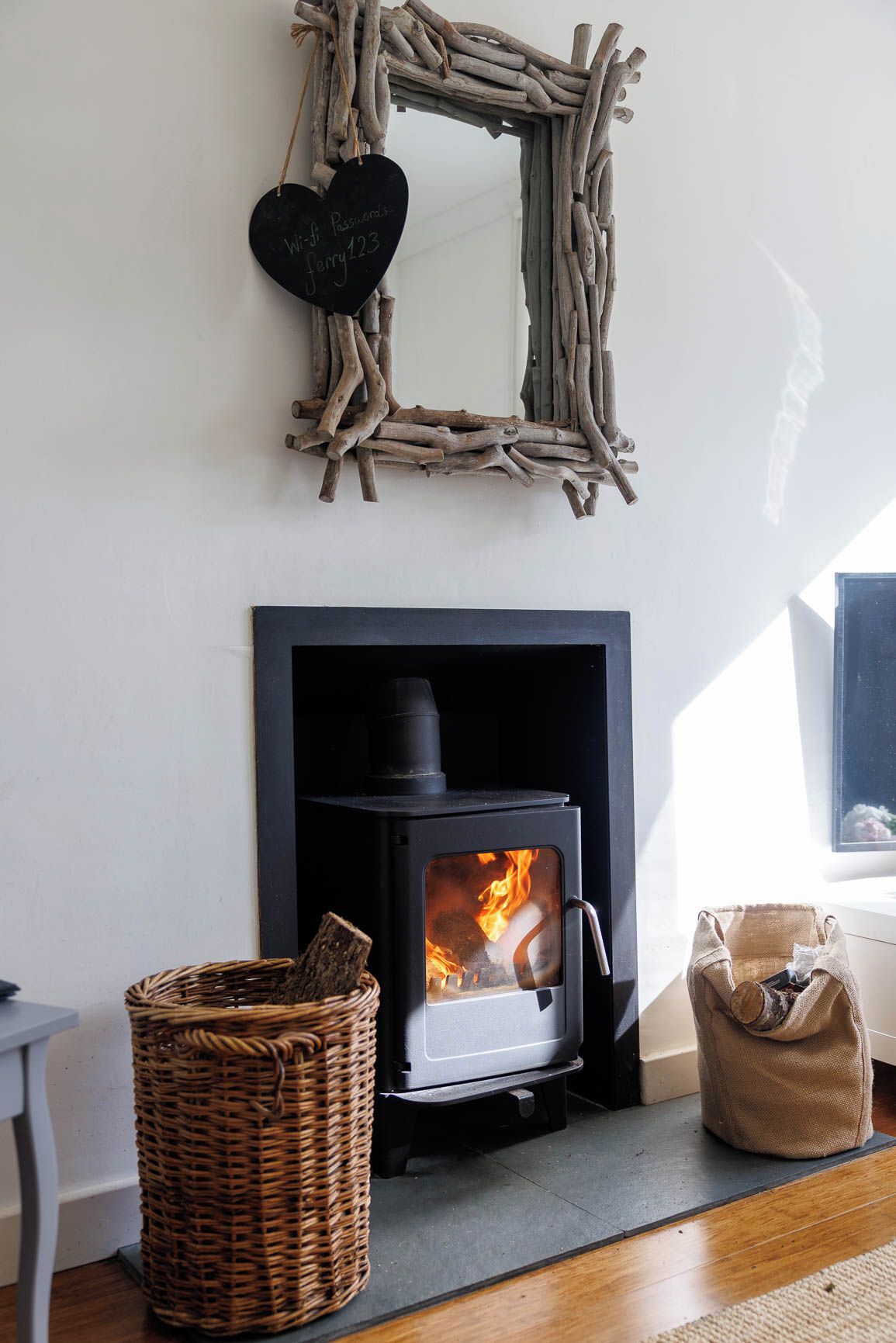 A room with a fireplace, a woven basket, and a heart-shaped sign with a Wi-Fi password.