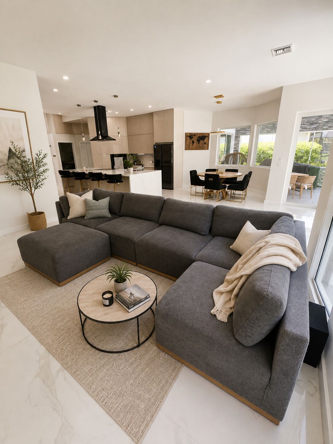 Ein modernes Wohnzimmer mit einem Ecksofa, einem Couchtisch und einem Essbereich mit Stühlen.