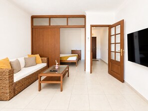 A modern living room with a sofa, coffee table, and a TV mounted on the wall. - Apartment Rocha | Sea View & Pool | Pulse (Praia da Rocha)