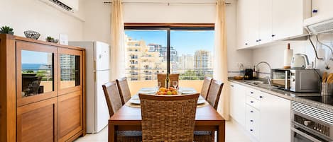 A modern kitchen with a dining area, featuring a dining table, chairs, a refrigerator, a microwave, and an oven.